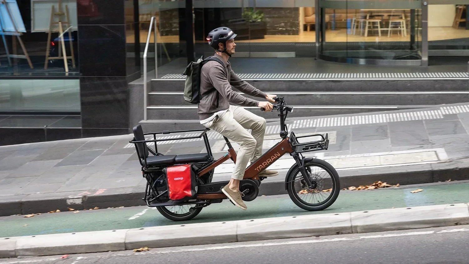 Urban commuter riding a TARRAN electric cargo bike with cargo bags