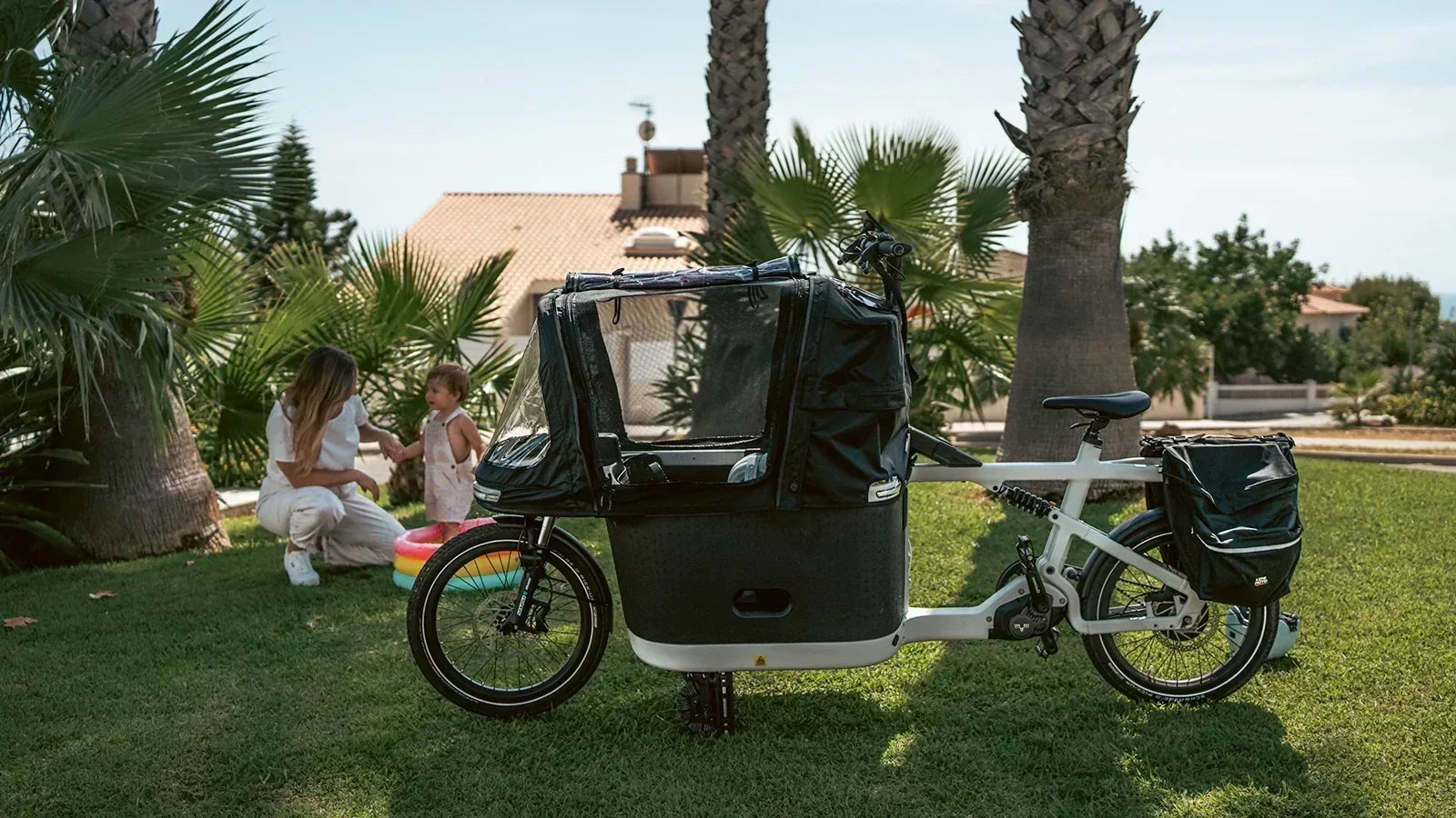 Cargo bike with a covered child compartment beside a family