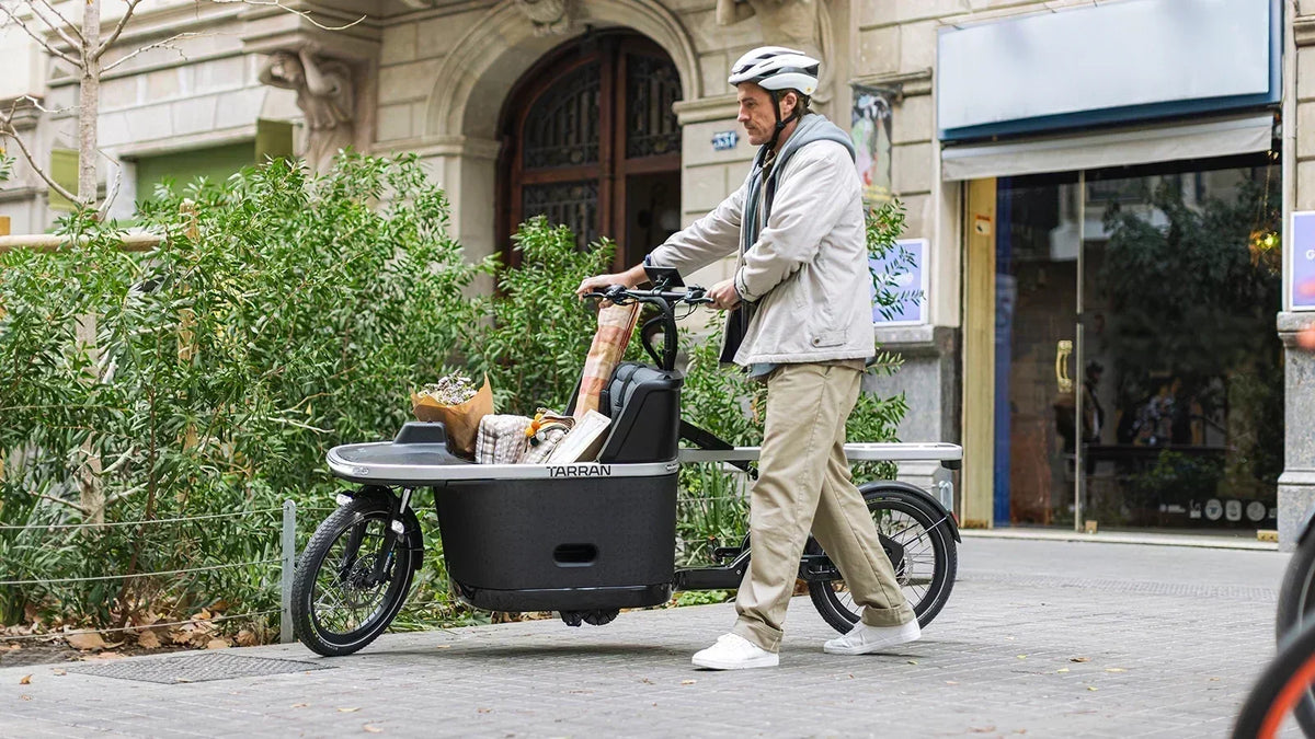 Man walking a loaded TARRAN electric cargo bike with groceries in the city