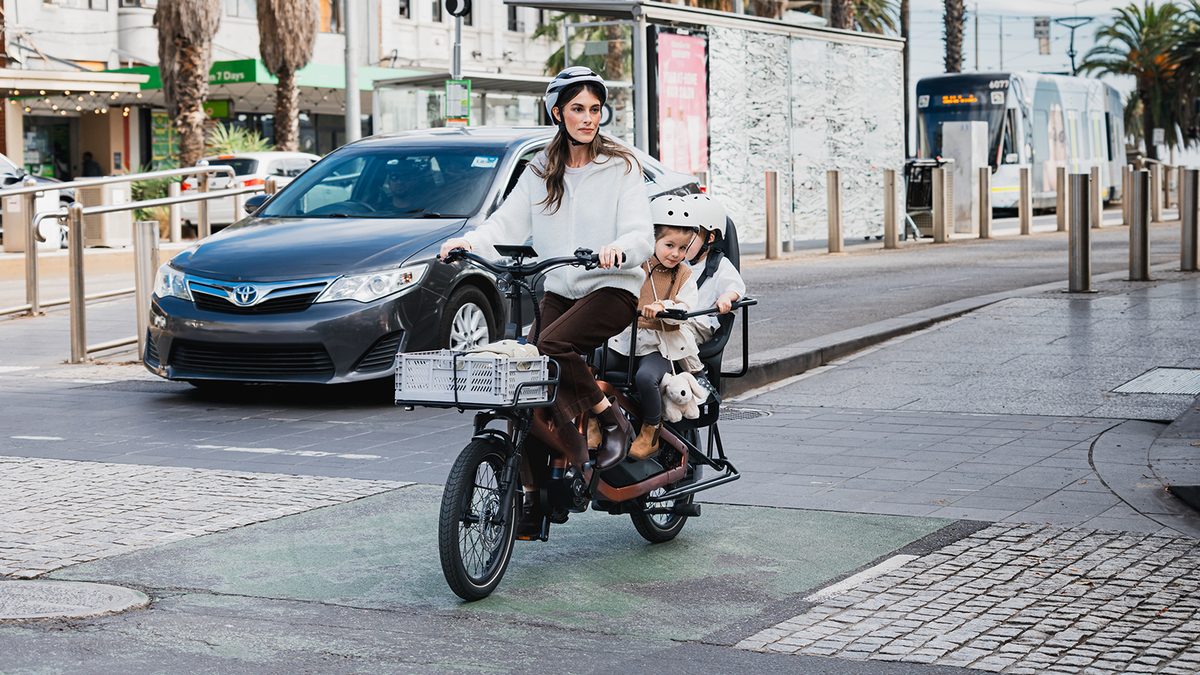 Parent à vélo cargo électrique TARRAN avec un enfant en ville